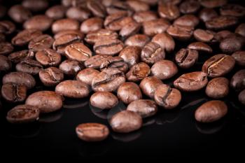 Fresh roasted coffee beans on black shine table. Closeup photo