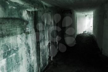 Empty abandoned bunker interior with glowing end of dark corridor, green toning photo filter effect