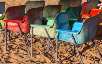 Old weathered colorful plastic chairs on the beach
