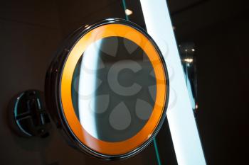 Round mirror with orange light in the bathroom