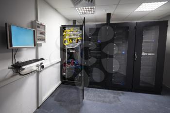 Modern server room interior with black computer cabinets and user terminal on the wall