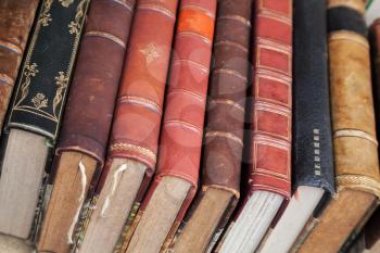 Old books with colorful leather covers lay on the market counter