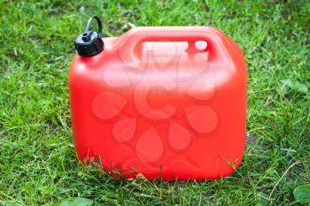 Red plastic jerrycan stands on green summer grass