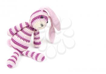 Knitted rabbit toy sits isolated on white background, selective focus with shallow DOF