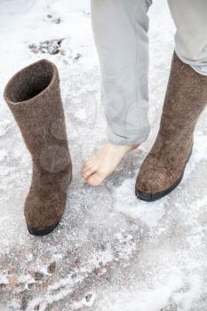 Male feet with traditional Russian gray felt boots stand on icy road