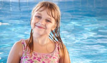 Portrait of a smiling little blond beautiful Russian girl with bright blue pool water on a background