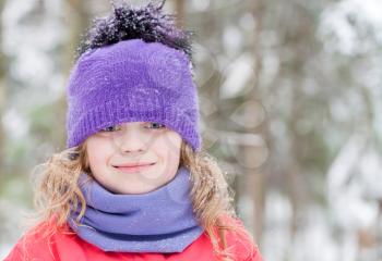 Little beautiful blond girl in winter outwear with snowflakes above forest background