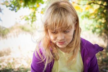 Portrait of the little smiling blond girl in autumn park