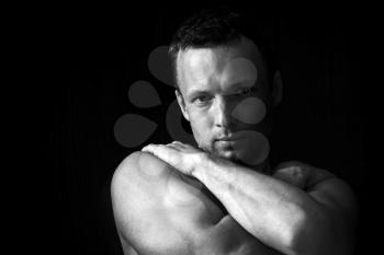 Strong muscular young Caucasian man portrait on black background