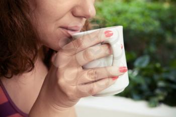 Woman holds white cup with coffee in her hands. Closeup outdoor photo