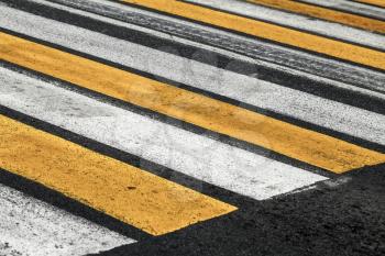 Pedestrian crossing road marking with yellow and white stripes on asphalt road