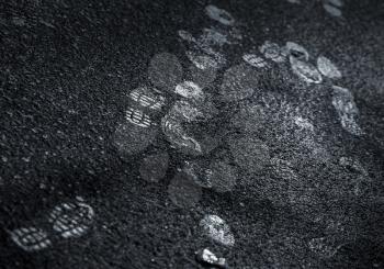 Shining footprints on the dark dirty asphalt road