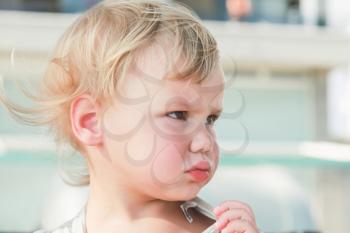 Outdoor close-up portrait of confused cute Caucasian blond baby girl