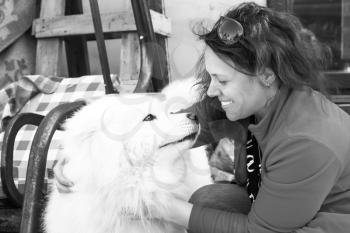 Happy young Caucasian woman with white fluffy Samoyed dog, monochrome photo