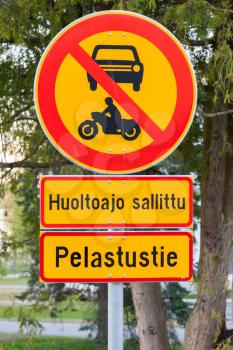 European round red and yellow traffic sign, the passage of vehicles and motorcycles is prohibited. Finnish text means Emergency exit, except official service vehicles