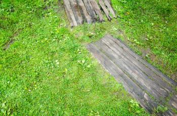 Old gray wooden decking on green lawn grass in park