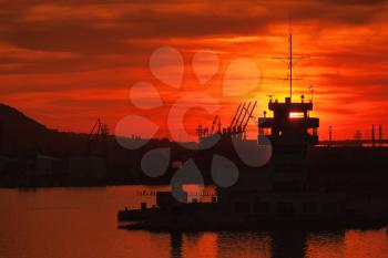 Black silhouettes of cranes and buildings of Varna port at sunset