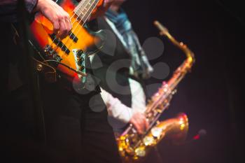 Live music background, guitar player and saxophonist on a stage with colorful illumination, photo with selective focus and retro tonal correction filter effect, old instagram style