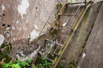 Rusted old metal ladder goes up on grunge concrete wall