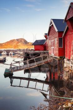 Vertical photo of Norwegian red wooden barns standing on the sea coast. Snillfjord, Sor-Trondelag region, Vingvagen fishing village