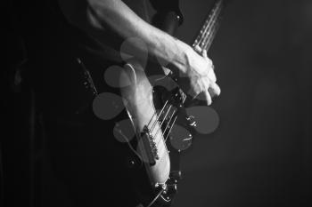 Closeup photo of bass guitar player hand, soft selective focus, live music theme, black and white