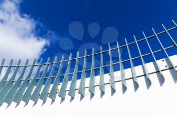 Metal fence on modern white bridge structure under blue cloudy sky