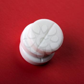Closeup of three white tablets on red