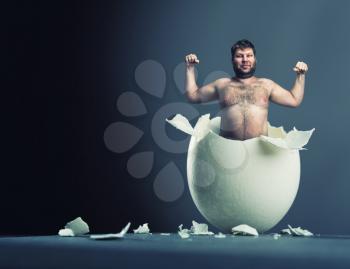 Close-up picture of broken egg with man isolated on gray background