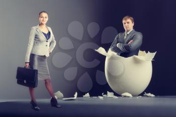 Picture of broken egg with man and woman isolated on gray background