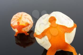 Figure of man of tangerine skin pushing a big tangerine over grey