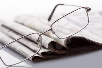 Closeup of glasses lieing on the newspapers