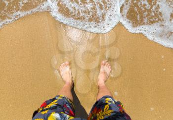 Up view of man's bare feet on the coastline