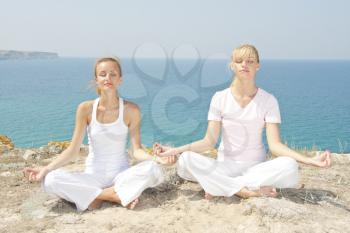Two woman in white meditating in mountains