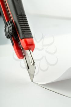 Closeup of office knife cutting paper