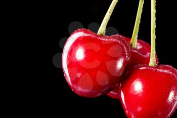 Three berries of cherry isolated on black background