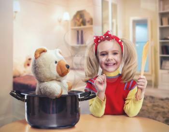 Happy little girl in the kitchen plays with her bear