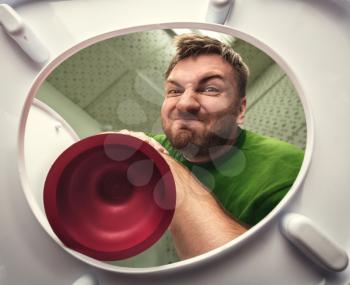 Man cleaning the toilet with cup plunger