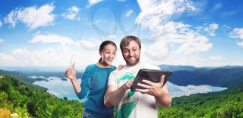 Excited man and woman playing with tablet outdoor