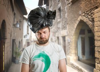 Sad man with trash pack on his head on the street