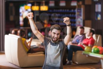Young bearded man celebrating his victory in bowling