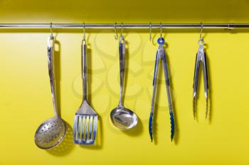 Cooking utensils on the hanger over yellow wall