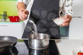 Close up of man's hand sifting sugar in the pan