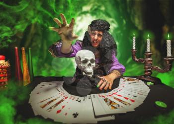 Strong sorceress practises witchcraft using pack of cards and the skull
