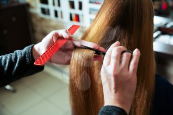 Cutting of hair with scissors and comb in hairdressing salon.