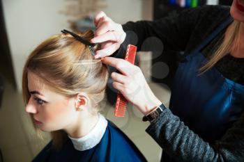 Hairdresser prepares for work with young woman in hairdressing salon.