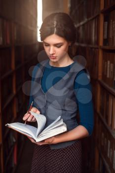 Student girl choose book with pen and notebook in her hands. Vintage library on the background.
