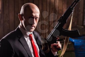 Contract killer holding machine gun in hand. Secret agent ready for mission. Hired murderer in suit and red tie hold automatic weapon. Brave professional agent wallpaper
