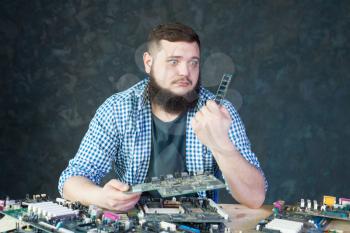 Male engineer work with broken computer components. Electronic devices repairing technology