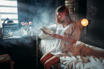 Young sick woman with book sitting on hospital bed. Illness of female patient in clinic