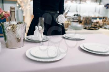 Waitress puts the glasses for dining, table setting. Serving service, festive dinner decoration, holiday dinnerware